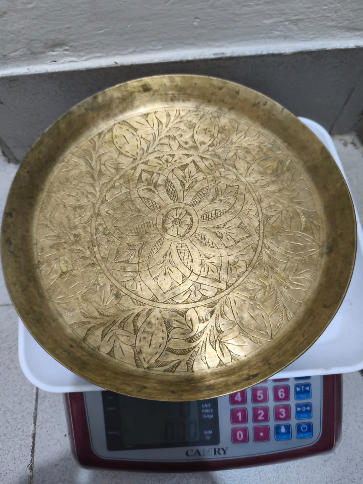 জটিল ফুল এবং পাতার নকশা সহ একটি আলংকারিক পিতলের প্লেট