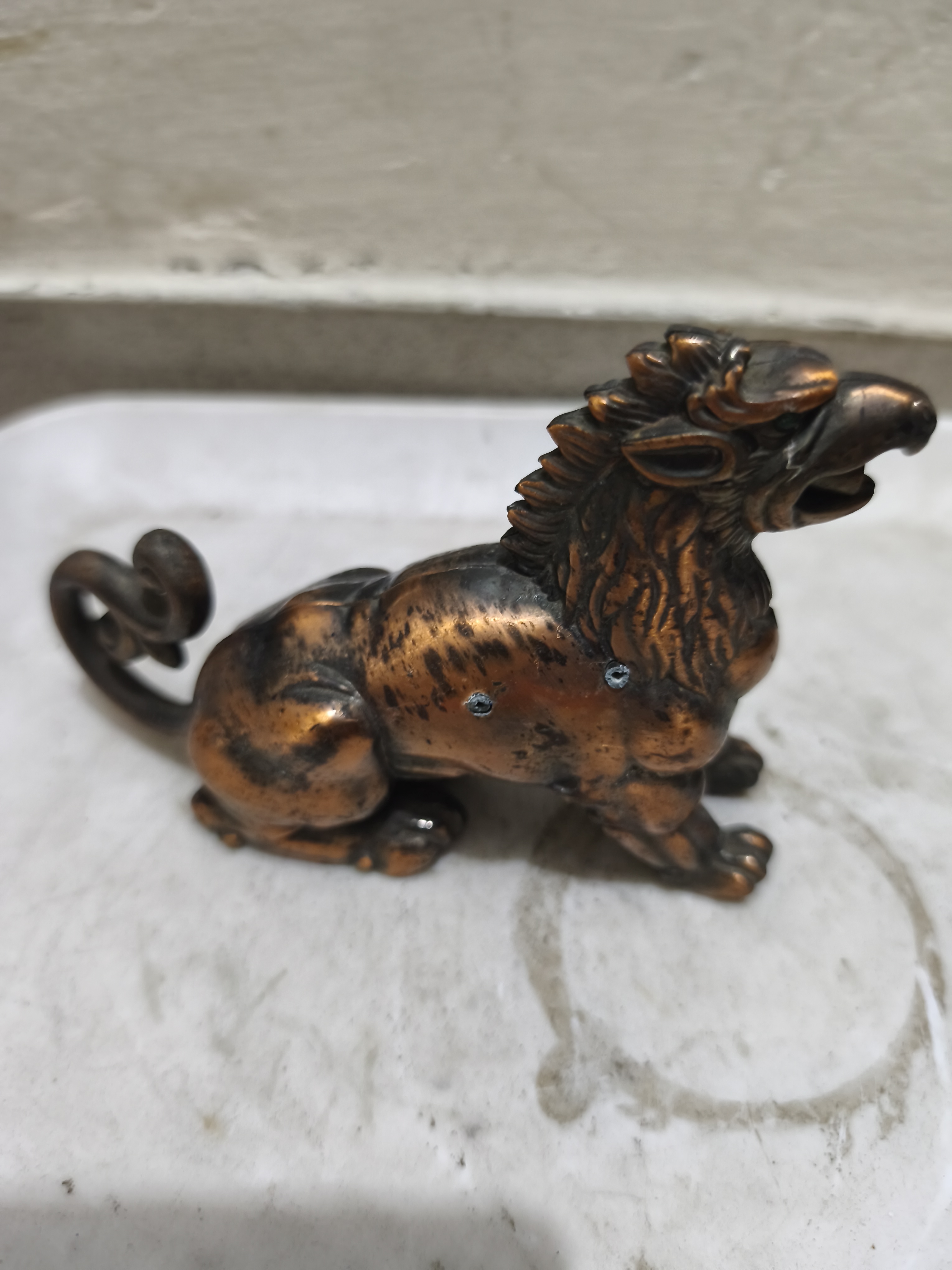 পিতল বা ব্রোঞ্জ বা তামার রঙের এই ছোট ভাস্কর্যটি  পিক্সিউ (Pixiu) বা শুভ্র জন্তু (Auspicious Beast