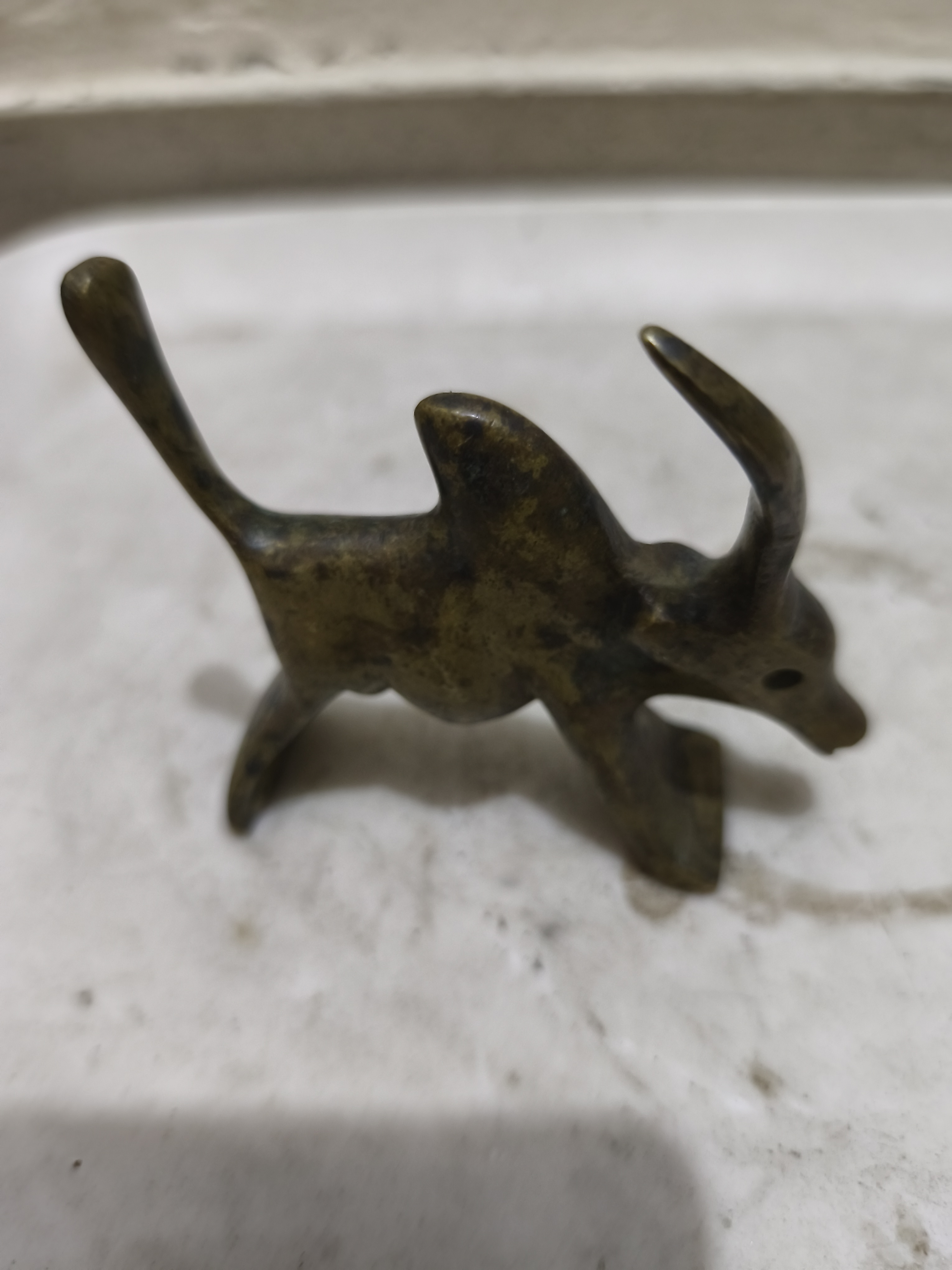 একটি ব্রোঞ্জ বা পিতলের তৈরি প্রাচীন শৈলীর ষাঁড়ের ছোট মূর্তিশিল্প।