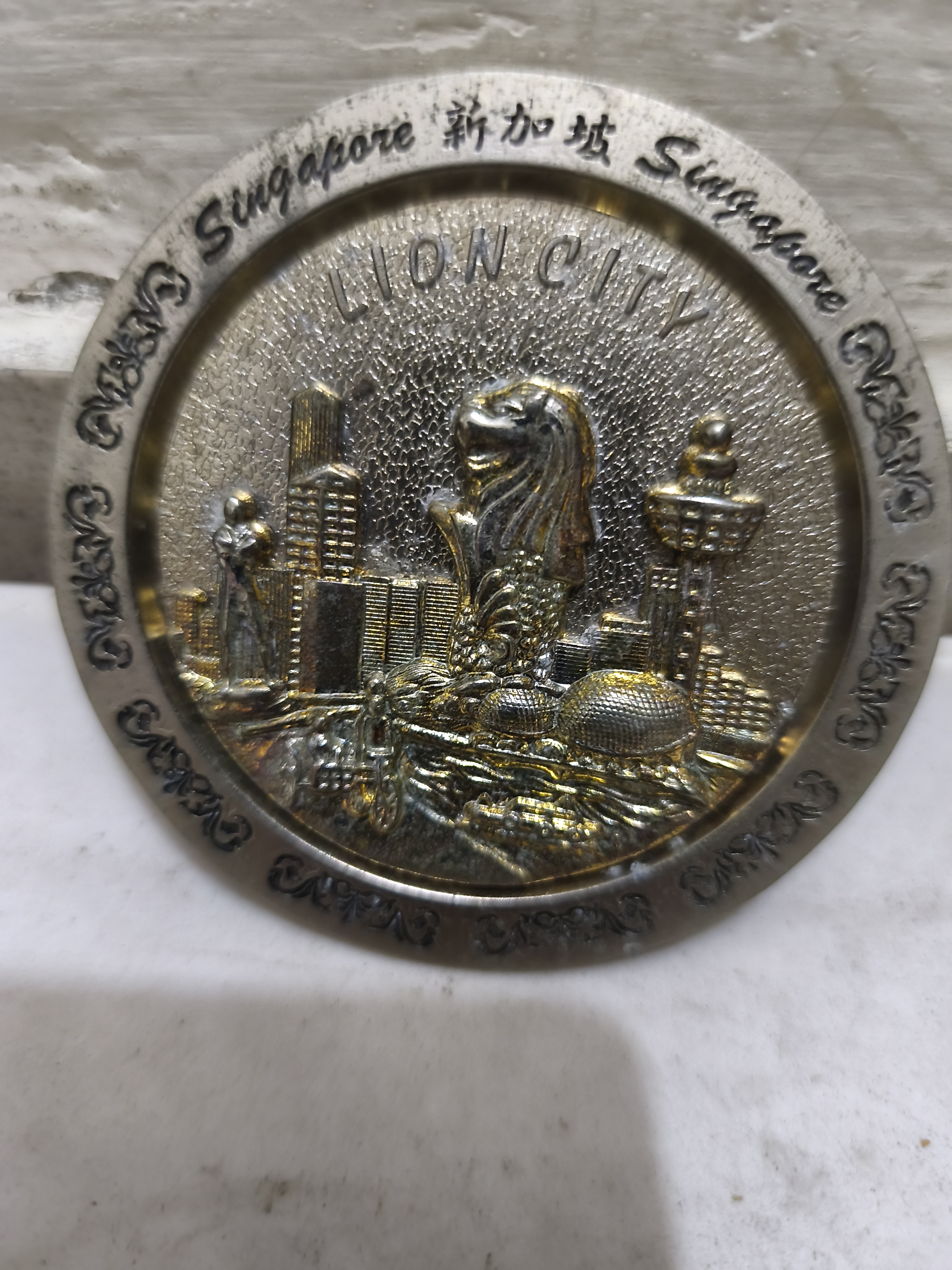 লায়ন সিটি সিঙ্গাপুরের একটি ধূসর রঙের ধাতব স্মারক ফলক পদক
